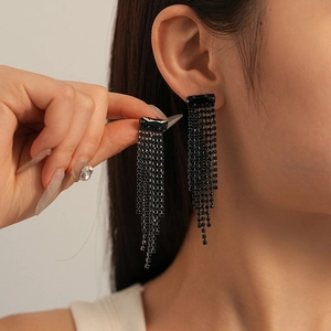 Macro detail of long black fringe earrings with tassels and shimmering crystals