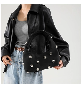 Detail of black crescent shoulder bag with silver stud accents styled with leather jacket