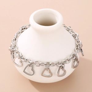 Detailed view of silver heart charms on a polished stainless steel link chain bracelet