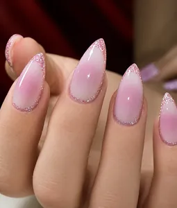 Detailed view of pink gradient almond press-on nails with fine glitter edges and glossy finish