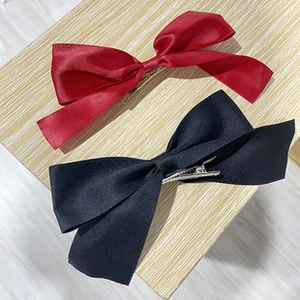 Detail view of red and black satin bow hair clips with metal alligator grip backing