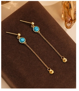 Macro detail of S925 silver gold-plated long chain earrings with blue turquoise stones