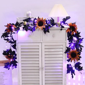 Detail of lit Halloween vine with black maple leaves, sunflowers, and mini pumpkins