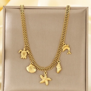 Détail du collier doré avec pendentifs étoile de mer coquillage et tortue marine