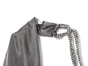 Détail du tissu satiné gris avec boutons blancs et bandoulière en perles gris argenté