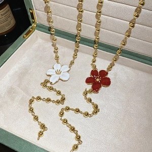Detail of elegant red and white floral necklaces with golden bead chain on green velvet