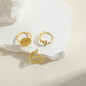 Set of 3 gold adjustable rings with devil eye and cross designs on stone stand