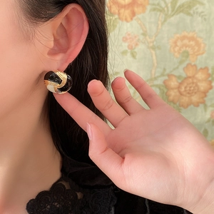 Dettaglio degli orecchini a bottone vintage tondi in smalto bianco e nero su modella