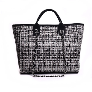 Dettaglio della trama in tweed bianco e nero con catena argentata della borsa tote