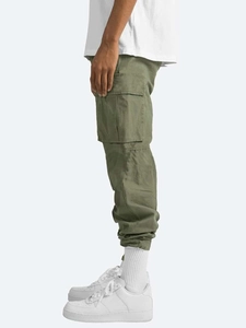 Detail view of olive green cargo pants showing large side flap pockets and cotton texture