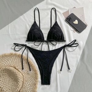Detail of black halter bikini featuring textured jacquard fabric and white pearl flower charms