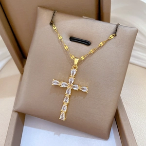 Macro shot of gold teardrop cross necklace with clear zircons in champagne box