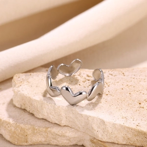 Macro shot of polished heart-shaped silver ring on a beige stone surface