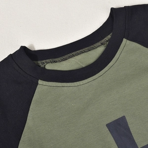 Détail du col rond contrasté et des coutures sur un t-shirt raglan vert armée