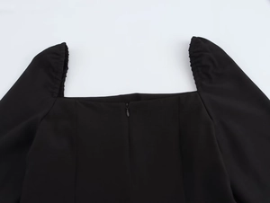Détail de l'encolure carrée et fermeture éclair invisible sur robe noire à manches