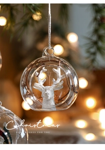 Macro view of transparent glass Christmas ball with white reindeer figurine inside