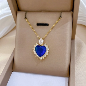 Close-up of heart-shaped dark blue zircon necklace with gold chain in a jewelry box