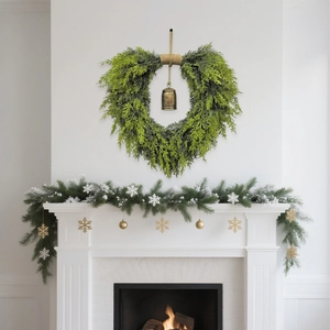 Christmas cedar heart wreath and garland set with bronze bells on white fireplace