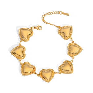 Detailed macro view of gold heart charm bracelet with polished beaded edges and lobster clasp