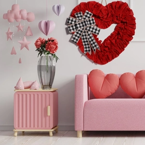 Detail of red fabric heart wreath with checkered bow hanging on a white wall
