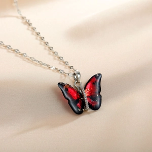 Detail of red and black butterfly pendant with pavé crystals on champagne silk