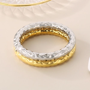 Detailed view of gold and silver stainless steel bangles with geometric quilted pattern