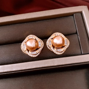 Macro detail of French style champagne pearl earrings with zircon inlay on dark velvet