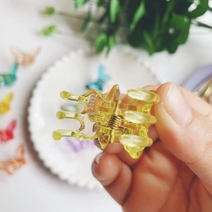 Detailed close-up of small colorful acrylic butterfly hair clips with metal springs