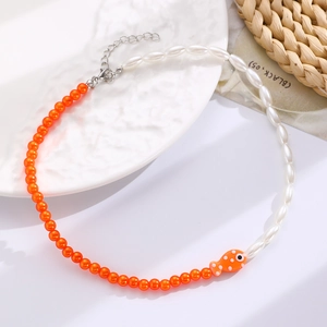 Detail of bohemian necklace with orange and white beads and cute fish pendant