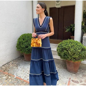 Détail de robe longue sans manches bleu marine avec broderie blanche et jupe à étages