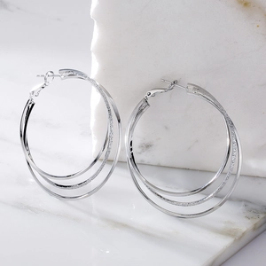 Layered silver geometric metal hoop earrings with polished and textured finishes
