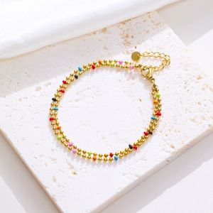 Detail of double-layer gold beaded bracelet with colorful enamel dots and lobster clasp