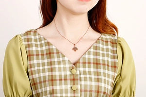 Close-up of a rose gold Tree of Life pendant necklace worn on a woman's neck