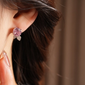 Dettaglio ravvicinato di orecchini a rosa rosa con foglia di zircone indossati con stile