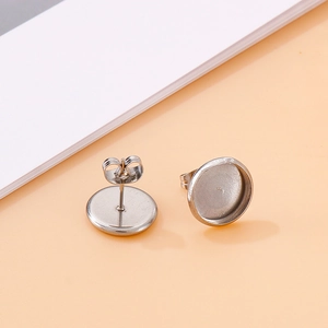Silver stainless steel round stud earring settings with butterfly backings on desk
