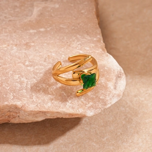 Detail of a gold adjustable ring featuring a square green gemstone on a natural rock