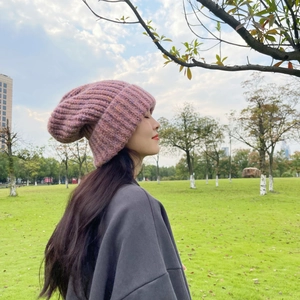 Detailed view of thick pink knit beanie with rolled edge texture in soft outdoor light