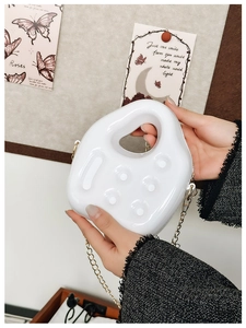 Close-up of white PVC jelly bag with unique controller shape and gold chain strap