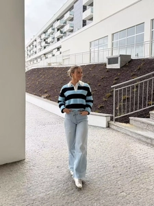 Detail of blue and black striped knit polo sweater paired with wide-leg jeans