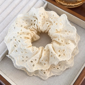 Detail of cream lace scrunchie with floral embroidery in a wooden jewelry tray