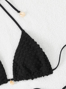 Detail of black bikini top featuring bubble texture fabric and shell charms on ties