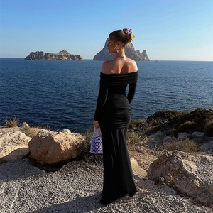 Elegantes schulterfreies schwarzes Maxikleid mit Raffungen vor einer Meereskulisse