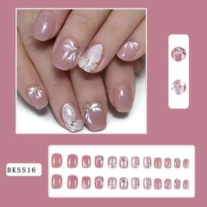 Detail view of pink-purple press-on nails with white hand-painted flowers and rhinestones