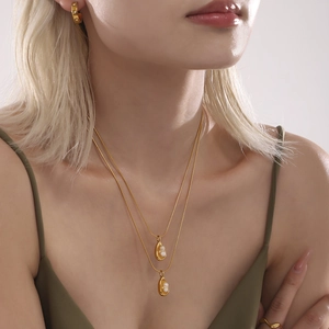 Double-layer gold stainless steel necklace with water-drop pearl pendants on a model