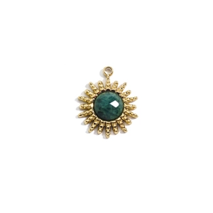 Detailed view of sunburst gold pendant with central green gemstone for DIY jewelry