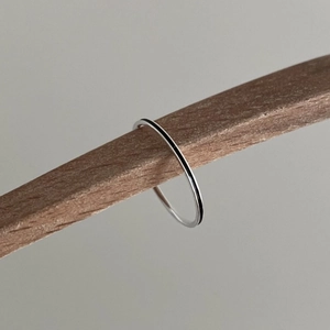 Minimalist 925 sterling silver slim band ring displayed on a natural wood stand
