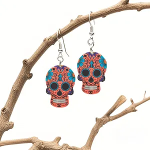 Detail of vibrant orange sugar skull earrings with floral relief on rustic wooden branches