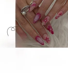 Détail de faux ongles en amande avec dégradé rose et motifs floraux 3D avec strass