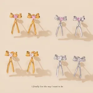 Detail of bow-shaped tassel earrings with heart-cut crystals in gold and silver finishes