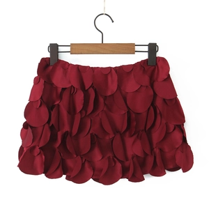 Détail d'une mini-jupe rouge foncé à pétales superposés avec texture soyeuse sur cintre